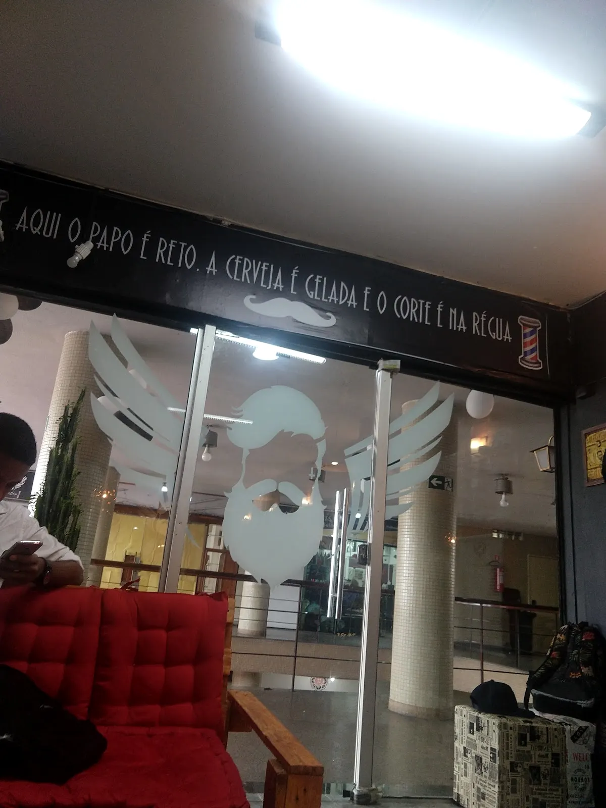 Parede da barbearia com a frase: aqui o papo é reto, a cerveja é gelada e o corte é na régua
